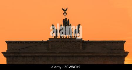 Sunset at the the Brandenburg Gate (German: Brandenburger Tor), an 18th-century neoclassical monument in Berlin, Germany. Atop the gate is a Quadriga, Stock Photo