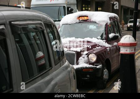 London, UK - December 01, 2010: Snow Covered London Taxi, also called hackney carriage, black cab. Traditionally Taxi cabs are all black in London but Stock Photo