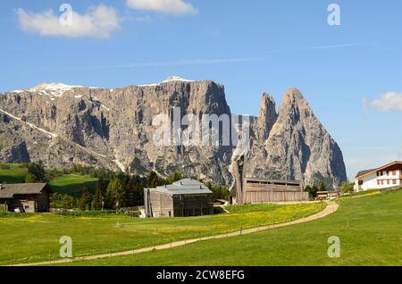 Seis, Italy - church in modern timber structure in mountain village compaccio on Alpe di Siusi and Punta Santner rock formation Stock Photo