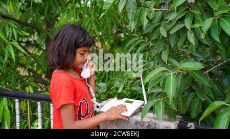 Indian children girl using telephone. Home alone concept Stock Photo