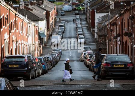 A young boy walking with his father to the Madrasah at the Masjid E Tauheed Mosque Oswald Street which lay within the Shear Brow and Corporation Park ward of Blackburn 2020. The area alongside a number of other areas in the North West and West Yorkhire have been place under additional government restriction in order to suppress the incidence and transmission  of covid 19. The Mosque reopend to its community on the 1st Spetember, 2020, under government covid 19 guidlines. During the Lockdown members of the mosque organised for food parcels to be delivered  to all communities in need within the Stock Photo