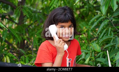 Little Indian girl seeing next to a vintage white telephone Stock Photo