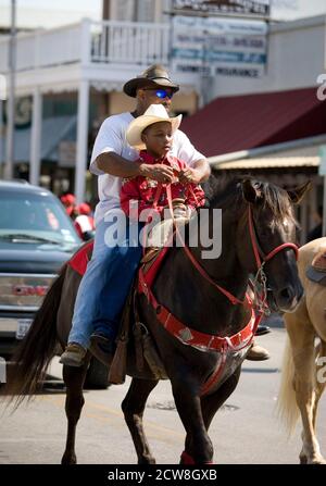 Bastrop, TX June 21, 2008: African-American cowboy and his son riding in a Juneteenth celebration in the historically African-American town of Bastrop near Austin. Juneteenth celebrates the day, June 19, 1865 when Union soldiers landed in Galveston, TX announcing the end of slavery and the Civil War. ©Bob Daemmrich Stock Photo