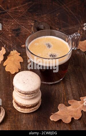 Glass cup of coffee and chocolate macarons on wooden background. Cozy autumn composition - Image Stock Photo