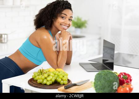 Black woman using laptop searching recipes looking at camera Stock Photo