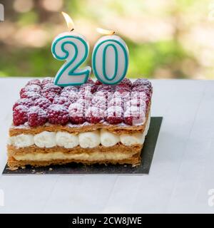 20th birthday raspberry cake with burning candles.Celebration. Stock Photo