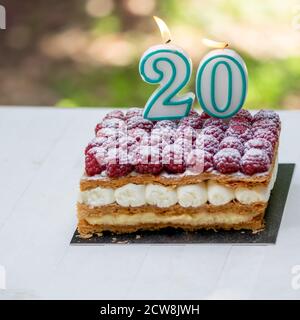 20th birthday raspberry cake with burning candles.Celebration. Stock Photo