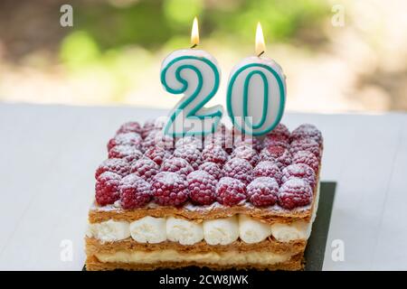 20th birthday raspberry cake with burning candles.Celebration. Stock Photo