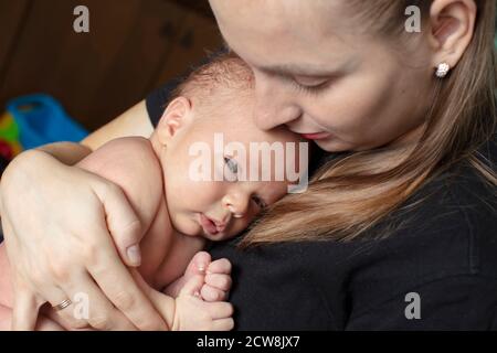 The newborn girl clung to her mother. Young woman with a baby. Stock Photo