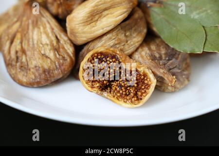 Dried figs in a white plate on a dark glass table Stock Photo