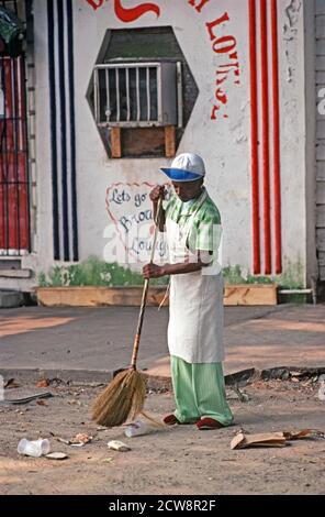 AFRICAN AMERICAN SWEEPING OUTSIDE CLUB, DOWNTOWN SAVANNAH, GEORGIA, USA, 1980s Stock Photo