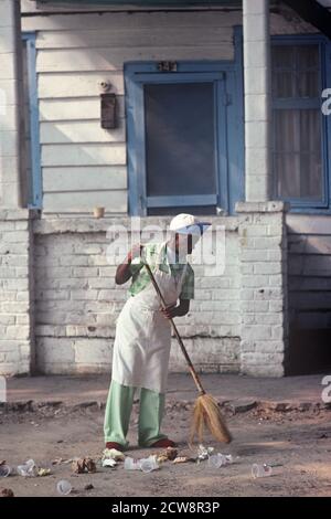 AFRICAN AMERICAN SWEEPING OUTSIDE CLUB, DOWNTOWN SAVANNAH, GEORGIA, USA, 1980s Stock Photo