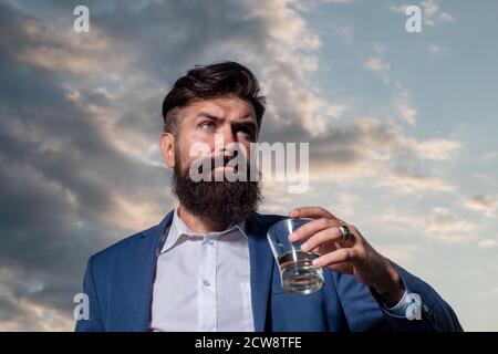 Man with beard holds glass brandy, drink cognac. Guy hipster tastes drink. Sipping whiskey. Luxury nightlife, rich bearded man drink expensive Stock Photo