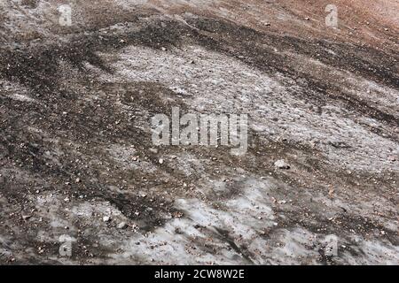muddy surface of a melting mountain glacier covered with rocks and rubble Stock Photo