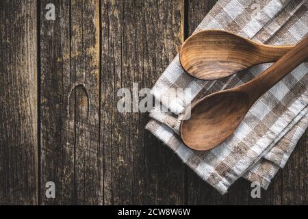 Two wooden spoons on checkered napkin on old wooden table. Top view. Stock Photo