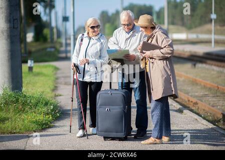 Group of positive senior people looking at map on traveling journey during pandemic.COVID-19 travel in the New Normal. Stock Photo