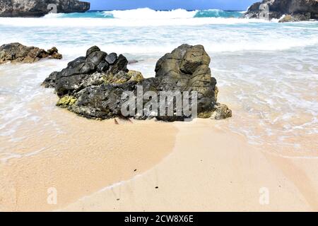 Big rock on a beach surrounded by the incoming tide in Aruba. Stock Photo