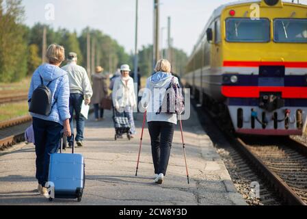 rear view of a group of seniors elderly people waiting for a train to travel Stock Photo