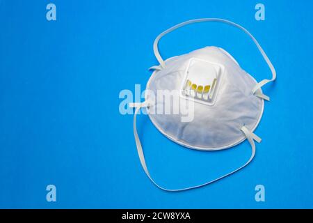 Protective mask with filter valve close-up on a blue background. Stock Photo