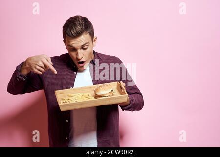 Man with wooden pallet fast food diet food lifestyle pink background Stock Photo