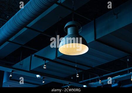 Black lamp hanging from the ceiling. Interior decoration of stylish bar. Modern style design. Black background Stock Photo