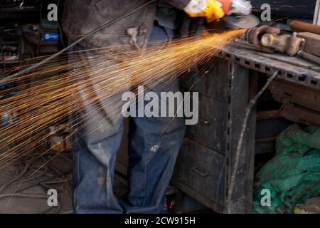 Welder used grinding stone on steel in manufacturing with sparks Stock Photo