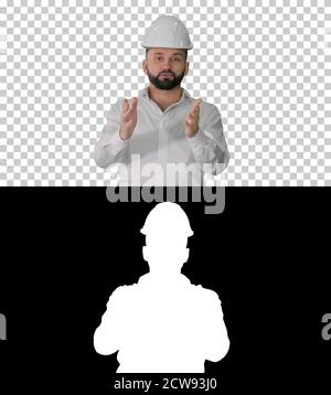 Engineer in a white helmet explaining something to camera, Alpha Stock Photo