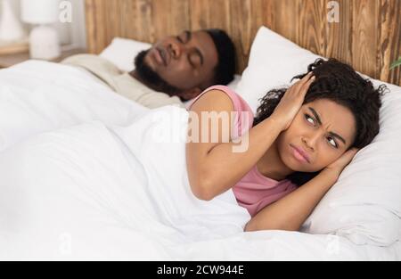 Annoyed black woman covering her ears with palms Stock Photo