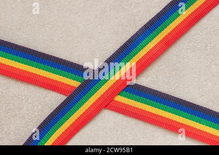 Two jute stripes of colorful rainbow color, lying crosswise on a gray background Stock Photo