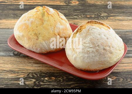Two small round loaves of French bread on red serving platter Stock Photo