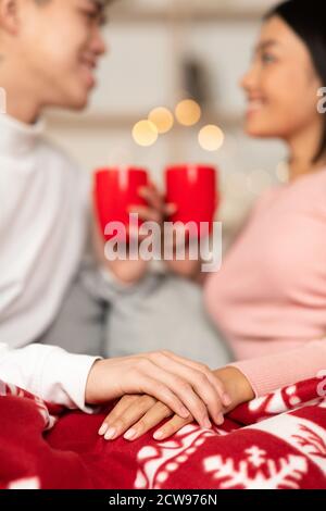 Japanese Couple Holding Hands Drinking Coffee On Christmas At Home Stock Photo