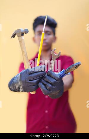 Handsome auto mechanic with tools on yellow backgrounds Stock Photo