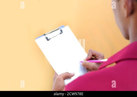 Close up of a young mechanic writing on a clipboard on a white and gray backgrounds Stock Photo