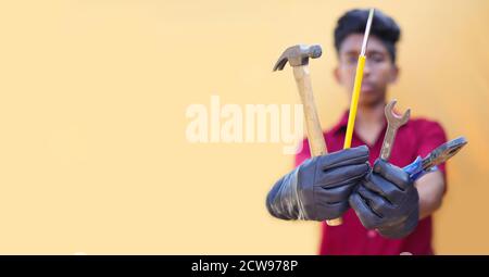 Handsome auto mechanic with tools on yellow backgrounds Stock Photo