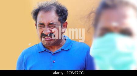 Coronavirus Precaution and Safety Tips. Sneezing man in blue shirt with virus around. Stock Photo