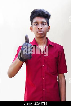 Young mechanic in uniform with showing thumbs up in gray backgrounds Stock Photo