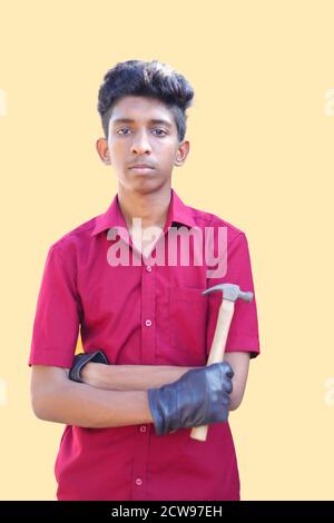 mechanic holding a hammer tool and cross arms on yellow backgrounds Stock Photo