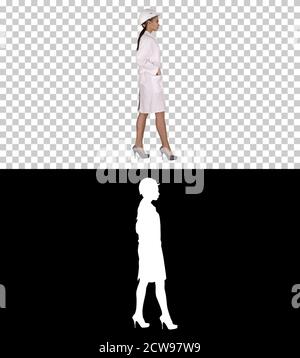 Woman in white robe putting hard hat on while walking, Alpha Cha Stock Photo