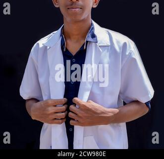 A close-up cropped portrait of a male doctor holding a white coat isolated on a black backgrounds Stock Photo