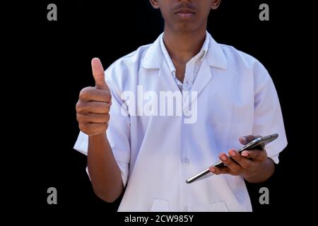 doctor giving you the good news by making the ok thumbs up gesture on black backgrounds Stock Photo