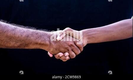 people concepts. Two men shaking hands isolated on black backgrounds Stock Photo