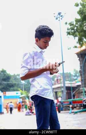 Young man using smartphone against background Hindu temples Stock Photo