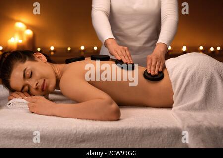 Joyful lady having hot stone massage at luxury spa Stock Photo