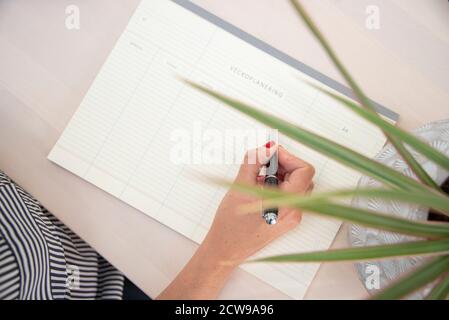 Close up of female hand with red nails writing in a weekly planner. Stock Photo