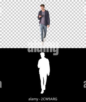 Young man in casual clothes text messaging on cell phone and wal Stock Photo