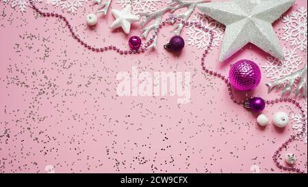Christmas and New Year white stars,snowflakes and purple Christmas balls and decorations among sparkles on pink background,top view,flat lay,copy spac Stock Photo