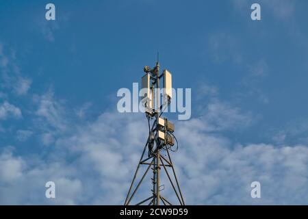Telecommunications tower with transmitters. Base station with transmitting antennas on a telecommunications tower against the blue sky. Stock Photo