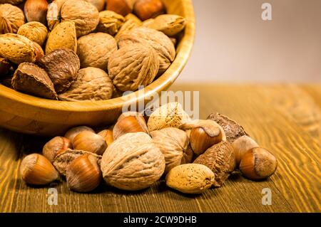 Mixed variety of nuts, walnuts, hazelnuts, almonds and macadamia nuts in a wooden bowl Stock Photo