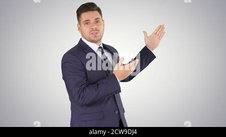 Smiling businessman pointing on something and talknig on gradien Stock Photo