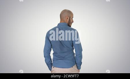 Arab in casual looking around with hands in pockets on gradient Stock Photo